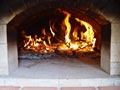 Photo of brick oven dome being heated up by wood fire.