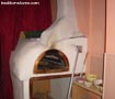 Picture shows a small sized wood fired oven in a pizza shop.