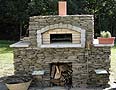 Backyard garden pizzaoven built of stones on outside.